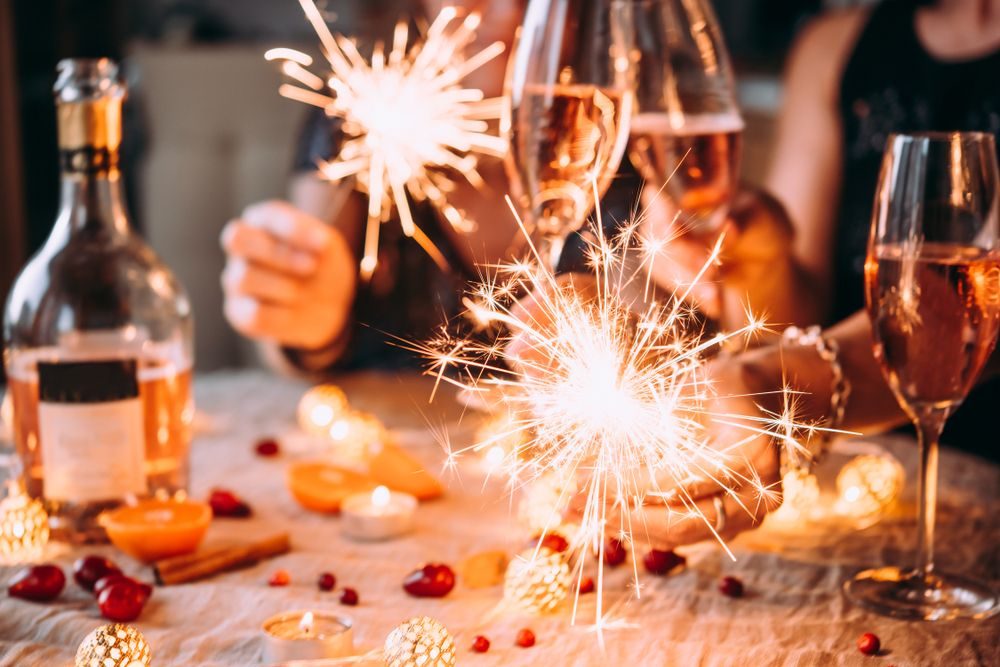 Menschen stoßen beim Geburtstag mit Sekt und Wunderkerzen an